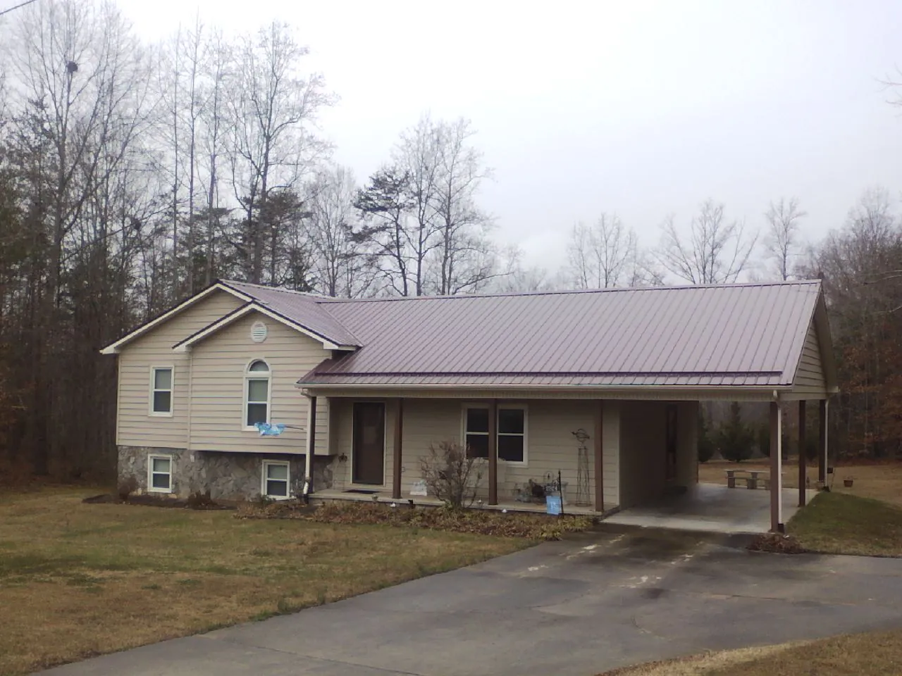 Burgundy metal roof on a tan split level home with an attached carport in Knob Noster