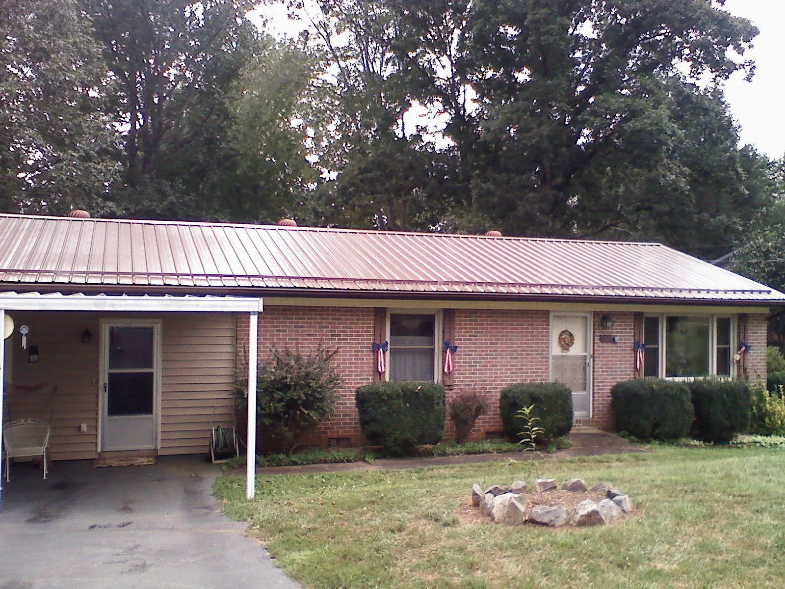 Bronze metal roof and carport on a brick ranch home — Roof Repair work by our crew in Knob Noster