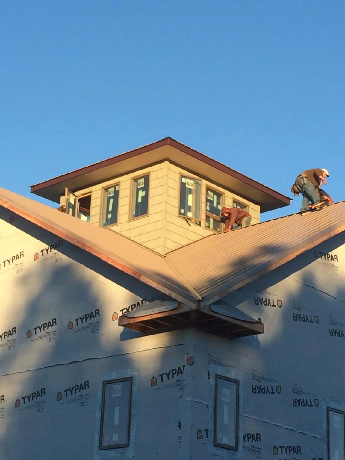 Roofers working around a rooftop cupola on a new metal roof at sunset — Roof Waterproofing in Knob Noster by Roofing Brothers